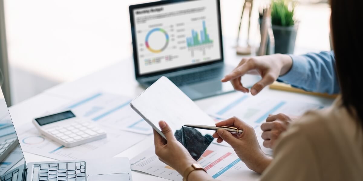 Marketing team analyzing SEO strategy and conversion metrics on a tablet with business reports and graphs.