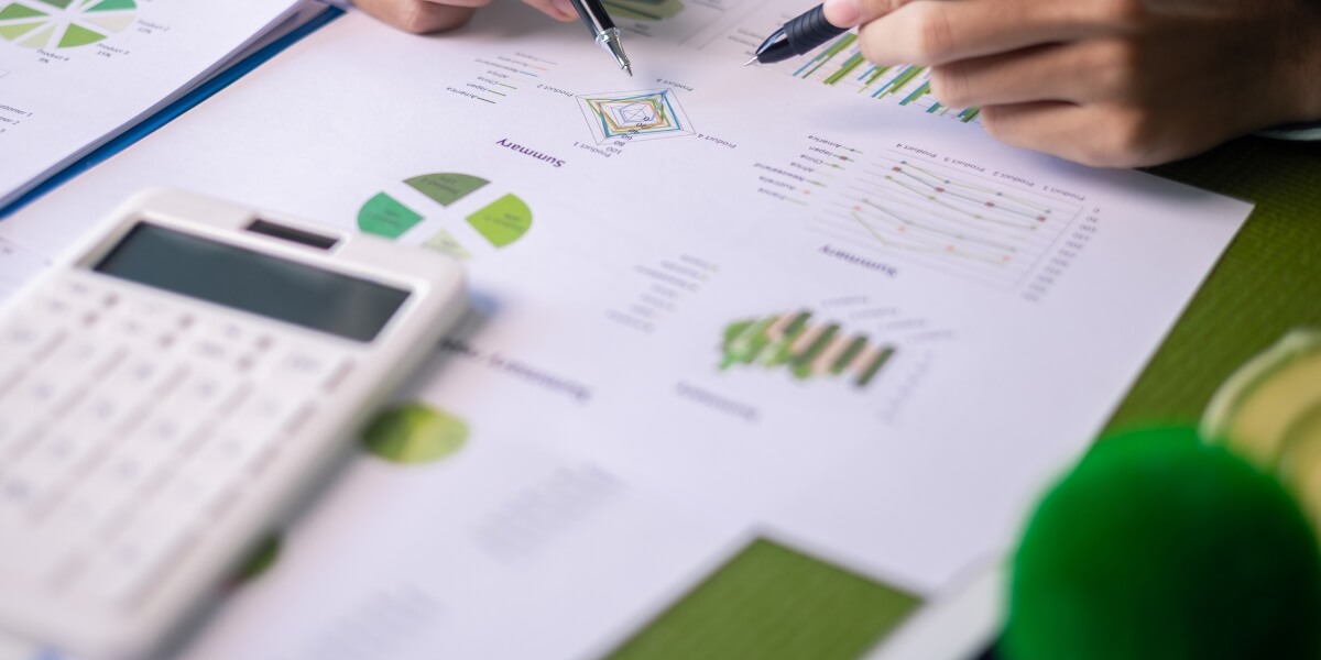 Close-up of hands analyzing SEO performance charts and data reports with a calculator, focusing on trends and key metrics.